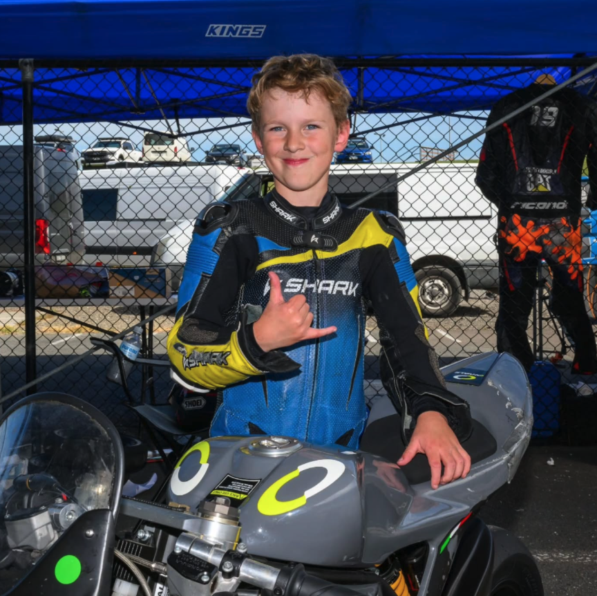 James in race leathers throwing a shaka beside his Ohvale